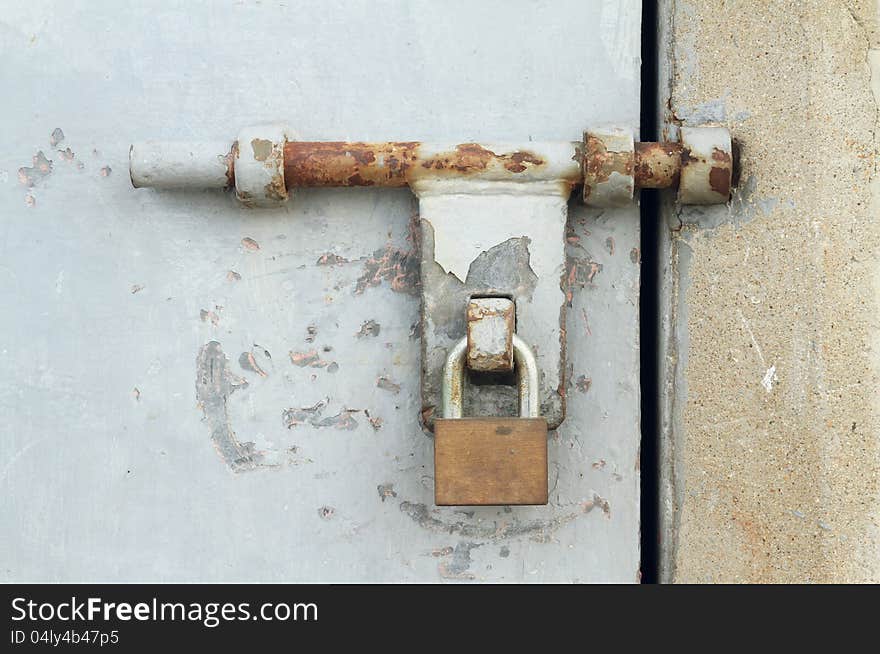 Rusty door latch with padlock of metal door