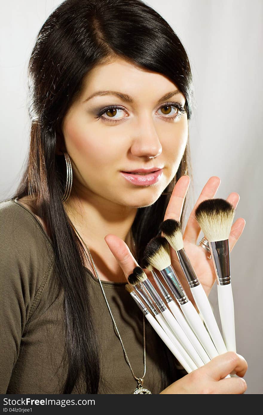 Beautiful woman with makeup brushes