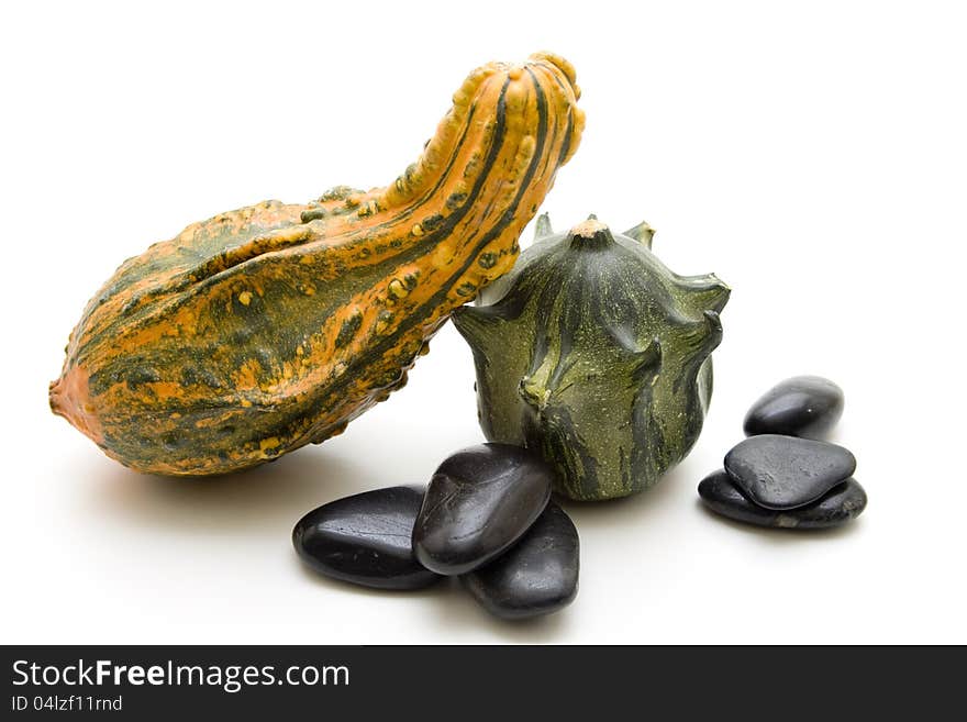 Pumpkins and black stones on white background