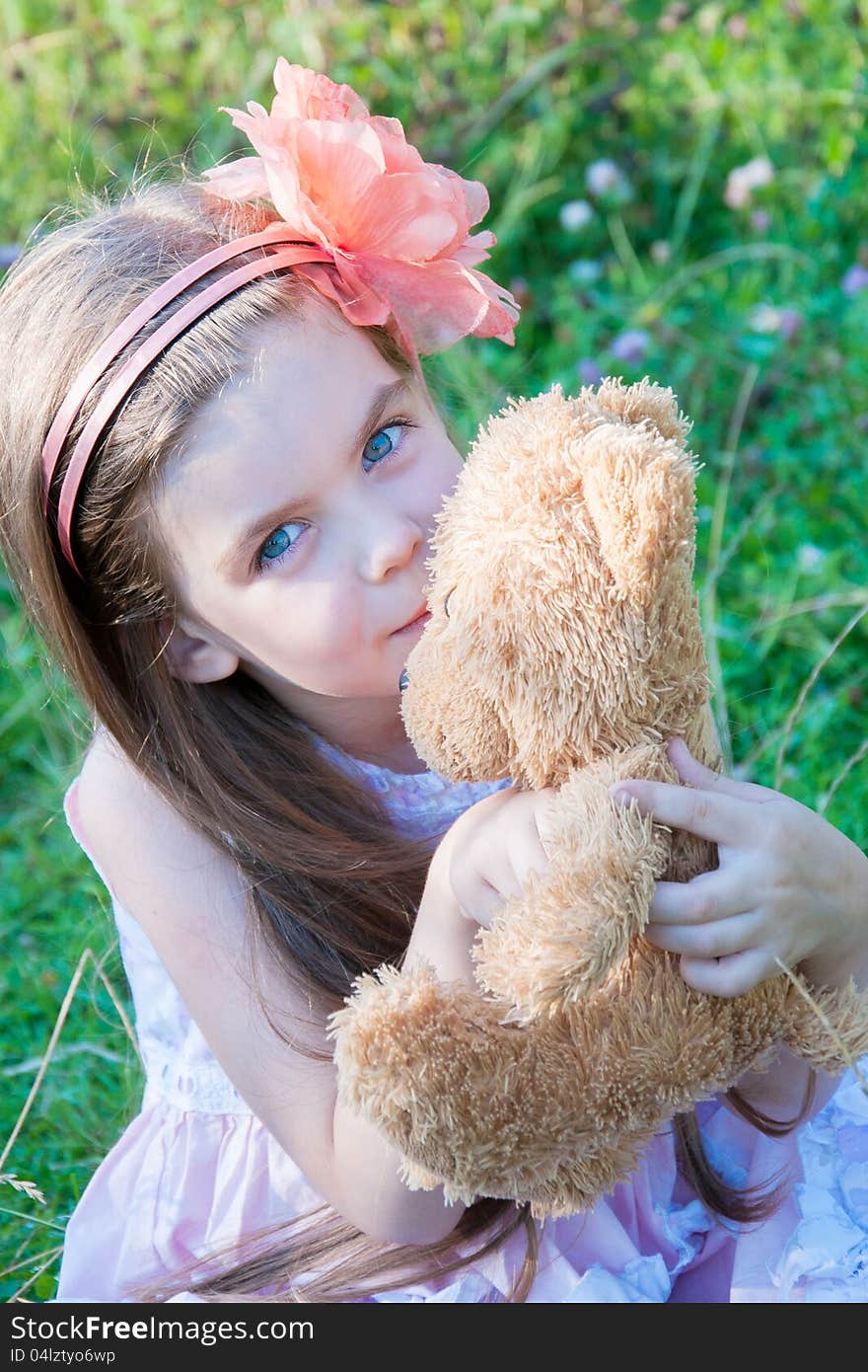 Happy little girl hugging a teddy bear against summer nature. Happy little girl hugging a teddy bear against summer nature.