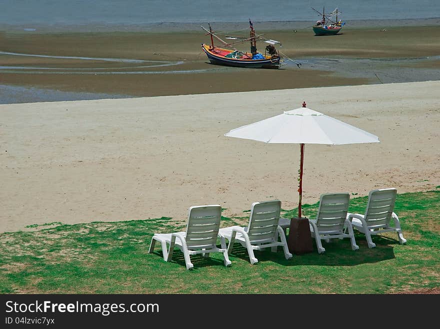 THE CHAIRS AND UMBRELLA ON GREEN GRASS AT SEASHORE