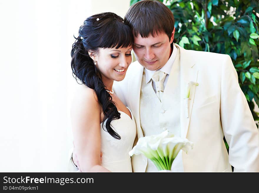 Happy bride and groom look at bouquet