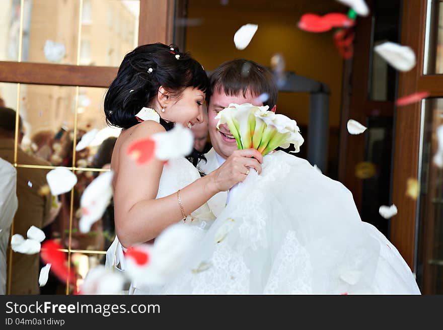 Happy newlyweds and flying red and white petals. Happy newlyweds and flying red and white petals