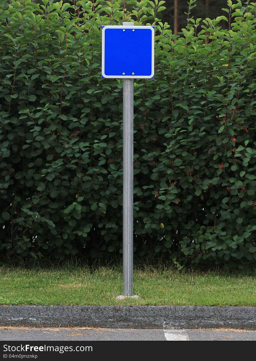 Blank blue sign on pole with green background. Blank blue sign on pole with green background.