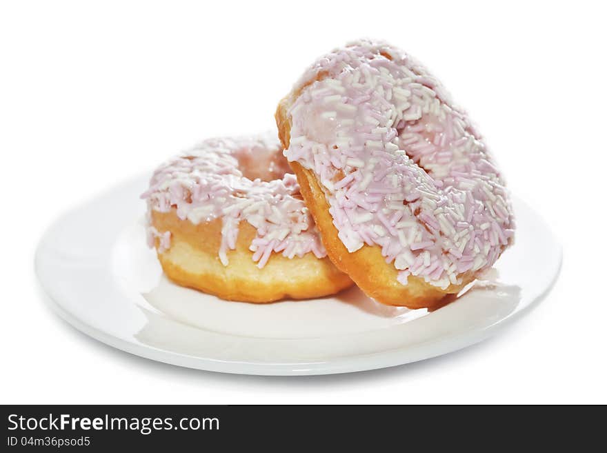 Closeup of iced and sprinkled doughnuts on plate isolated on white