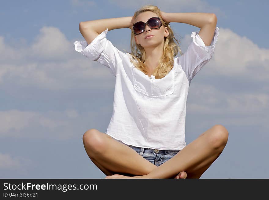 Portrait of beautiful blonde girl in sunglasses on background blue sky. Portrait of beautiful blonde girl in sunglasses on background blue sky