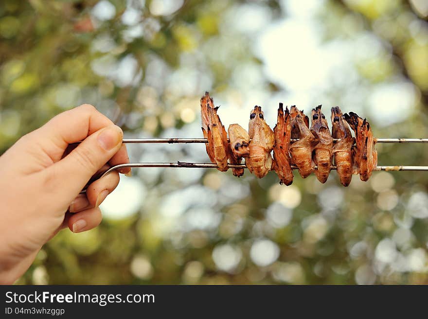 The hand of the person holds on skewers fried shrimps. The hand of the person holds on skewers fried shrimps