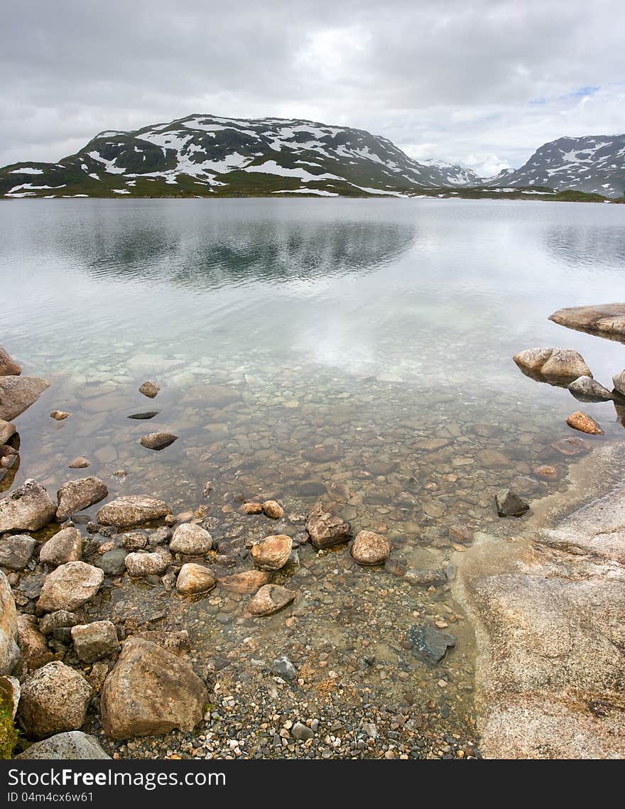 Norwegian landscape with a mountain on background and mountain lake