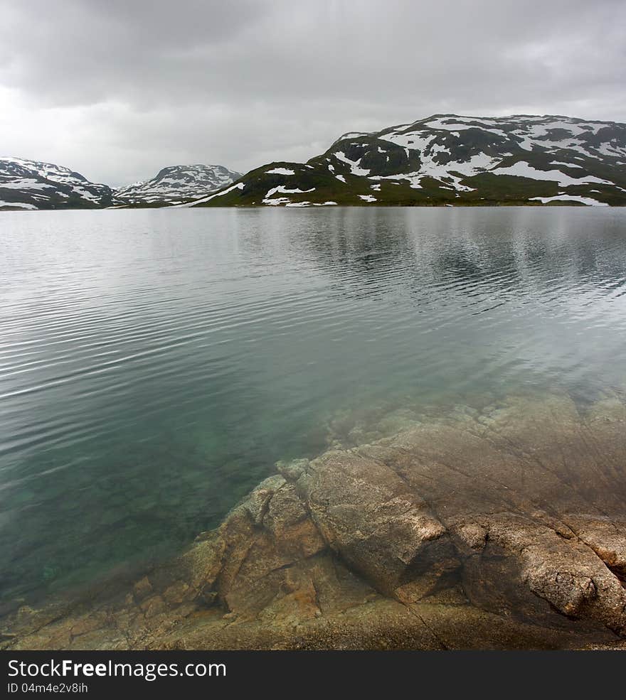 Norwegian landscape with a mountain on background and mountain lake