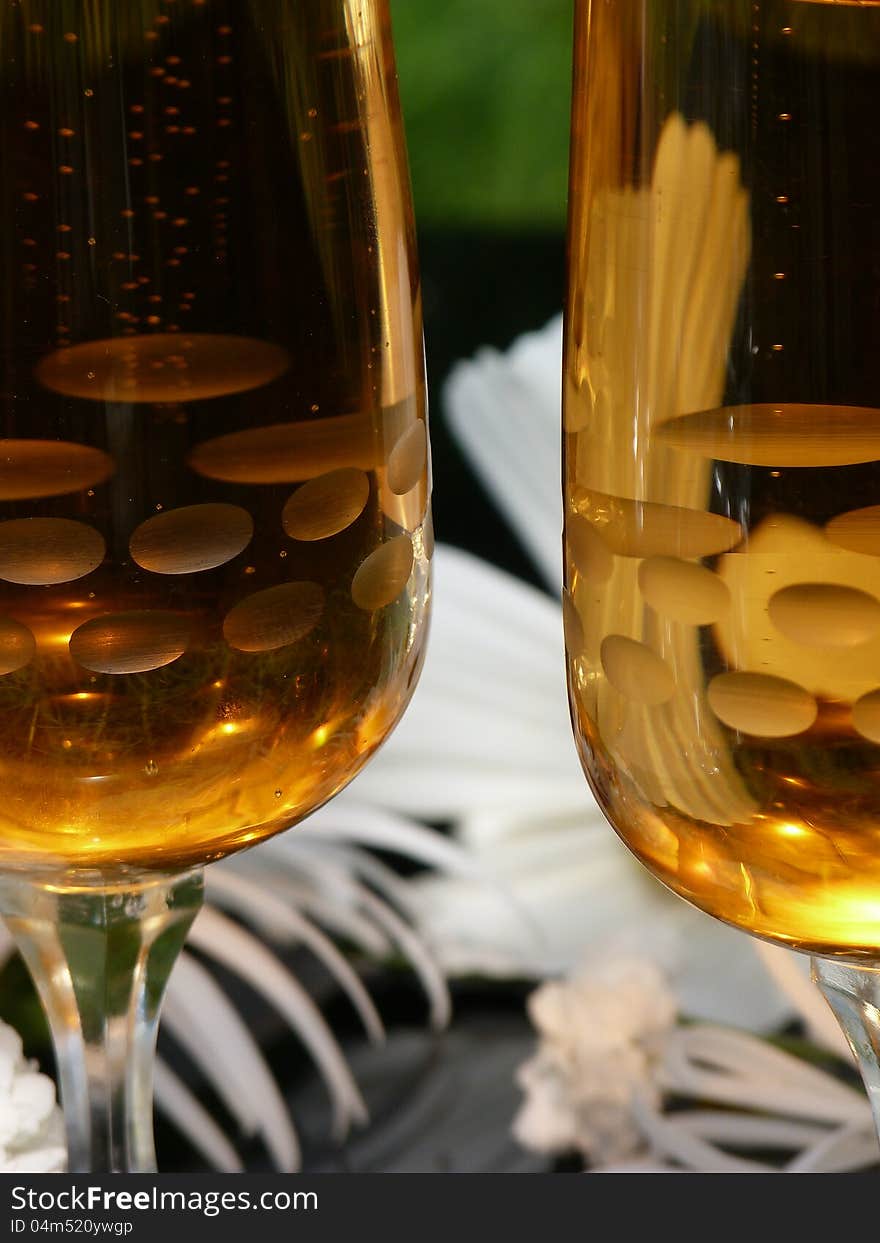 Two glasses of sparkling wine with white flowers on black