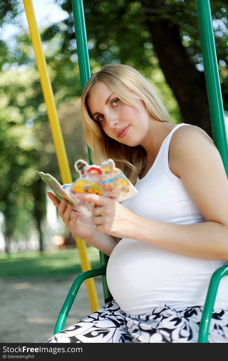 Pregnant girl in a park with a book