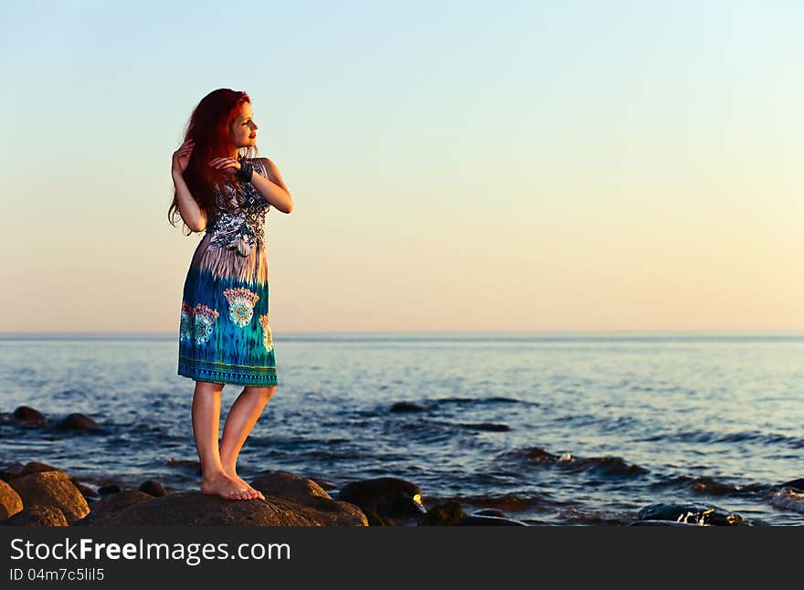 Beautiful girl on seacoast before a sunset