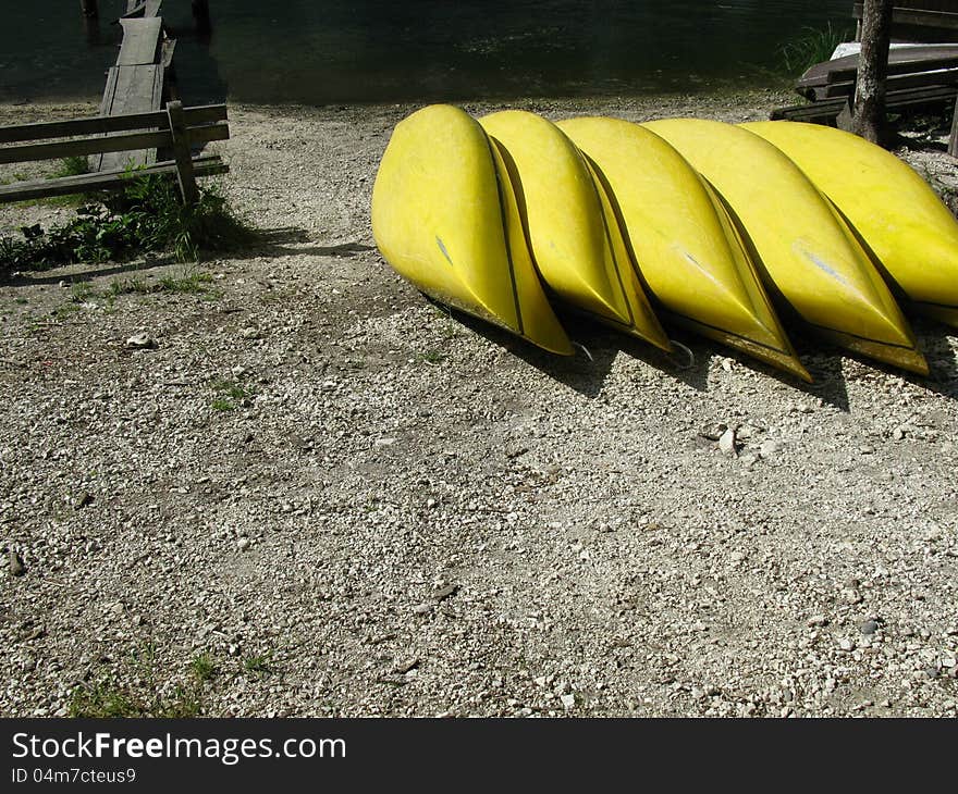 Yellow canoes in a row on the beach of a lake. Yellow canoes in a row on the beach of a lake