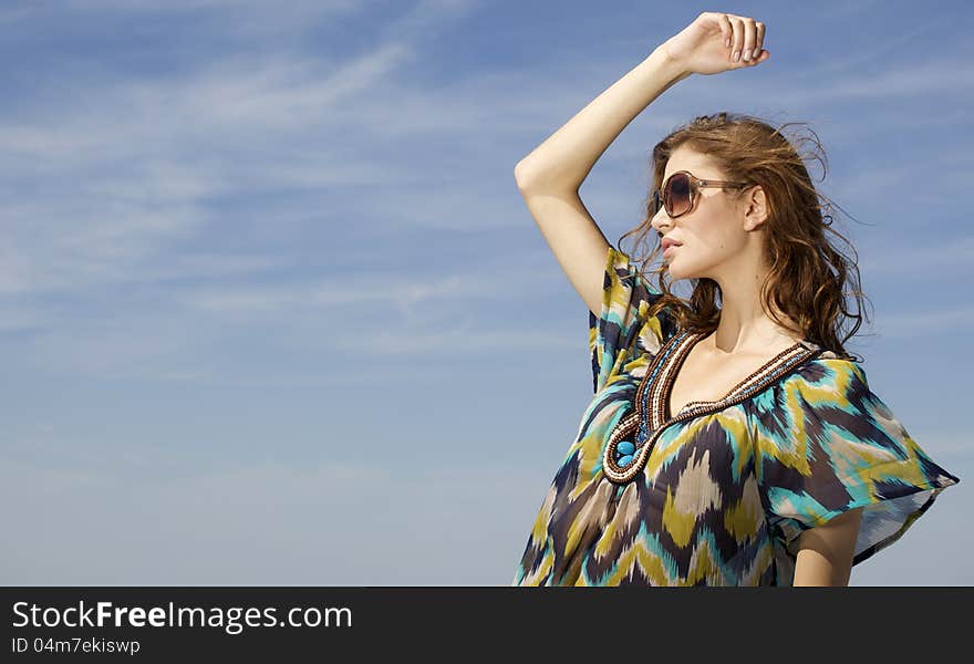 Portrait of beautiful brunette girl in sunglasses on background blue sky. Portrait of beautiful brunette girl in sunglasses on background blue sky