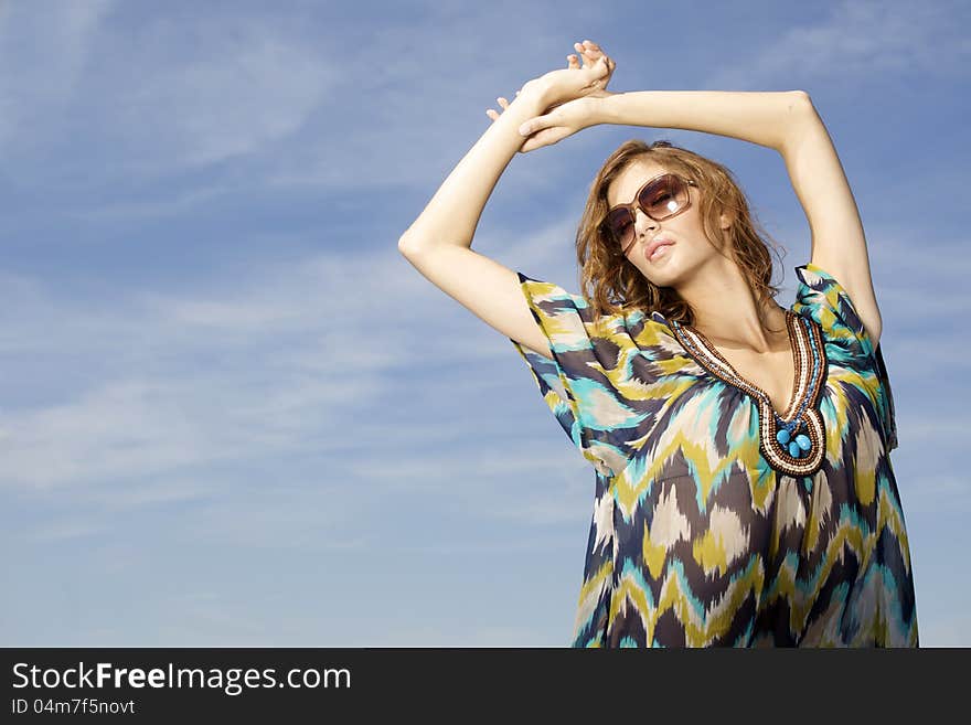 Portrait of beautiful brunette girl in sunglasses on background blue sky. Portrait of beautiful brunette girl in sunglasses on background blue sky