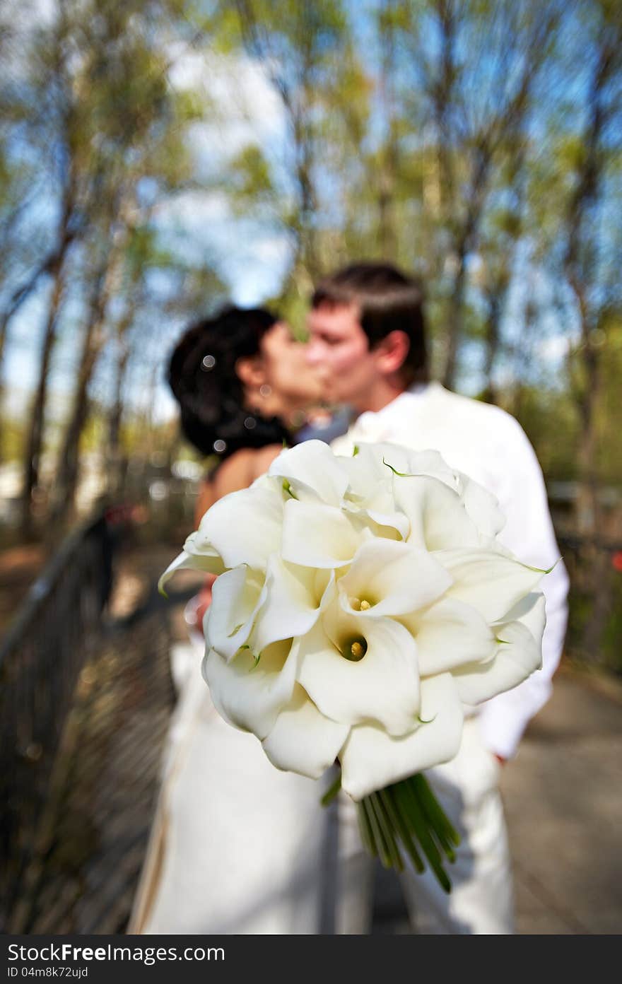 Bouquet Kala Against Romantic Kiss Bride And Groom