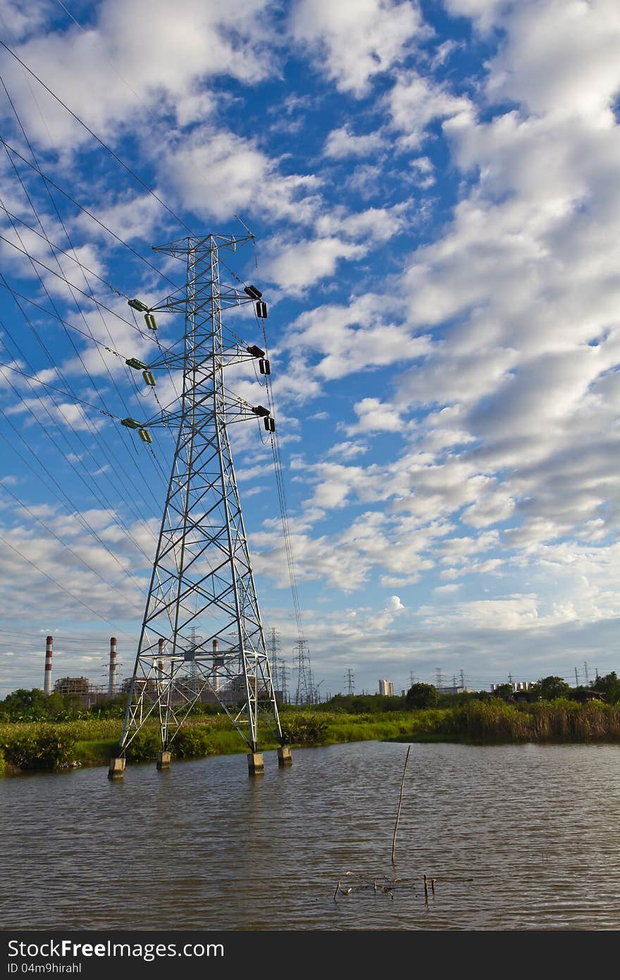 High voltage power transmission lines and pylons with gas turbine electrical power plant in background, Thailand