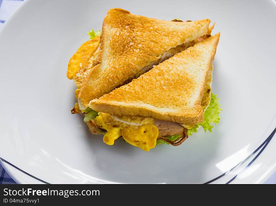 Sandwich with sliced meat loaf, cooked egg and vegetables, serving on white dish. Sandwich with sliced meat loaf, cooked egg and vegetables, serving on white dish