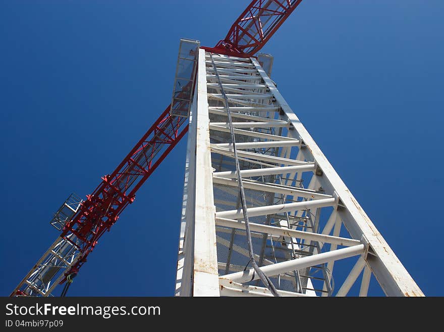 White crane with red jib against blue sky. White crane with red jib against blue sky