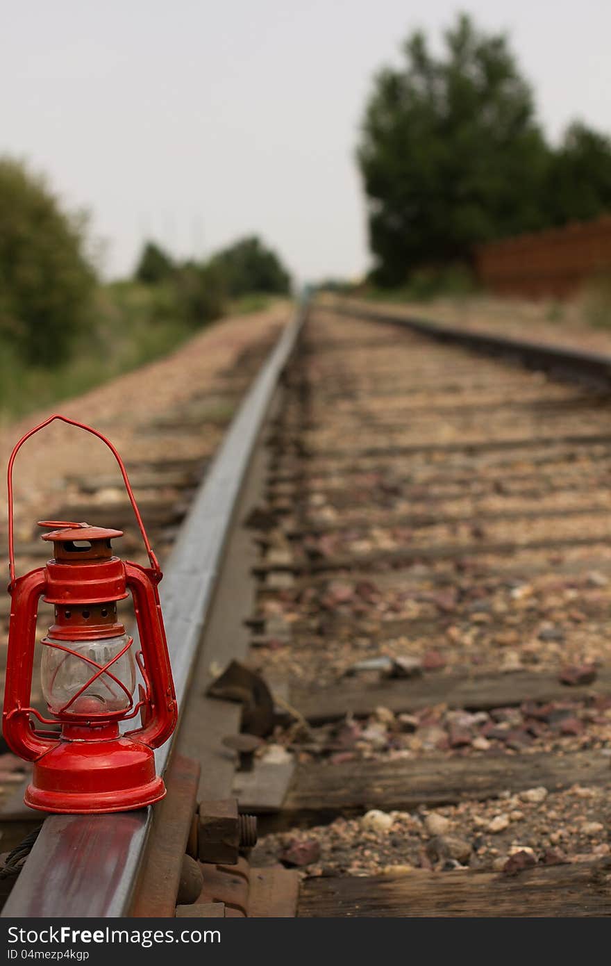 A antique red gas lantern on railroad tracks. A antique red gas lantern on railroad tracks.