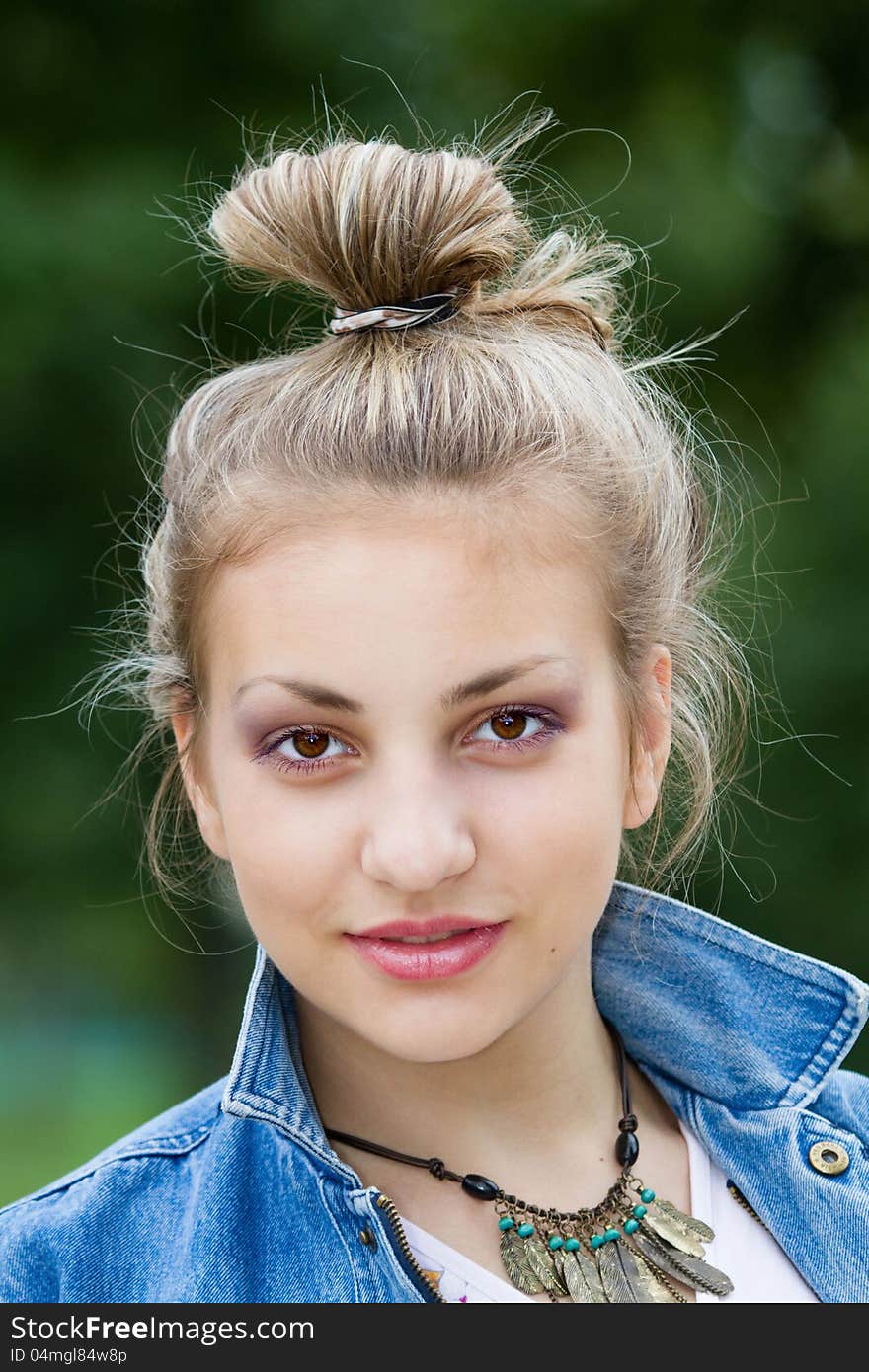 Face of a beautiful girl on the background of green leaves