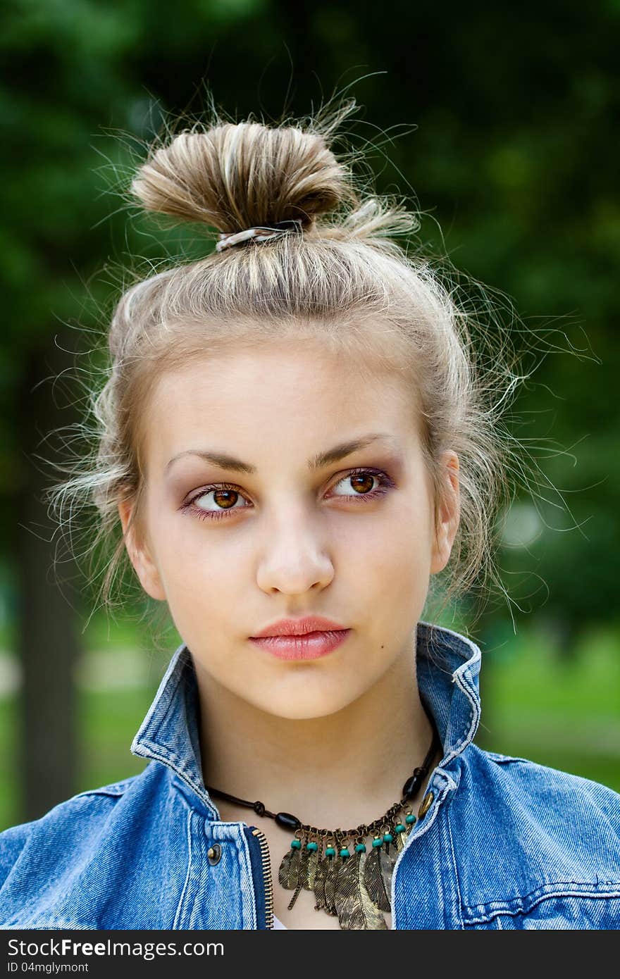 Face of a beautiful girl on the background of green leaves