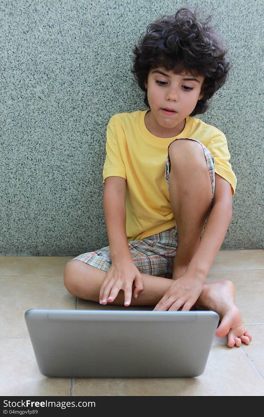 A boy sitting on the floor and working on his laptop. A boy sitting on the floor and working on his laptop