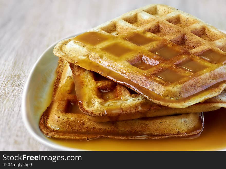 Stack of homemade waffles on the plate with sweet sauce on top