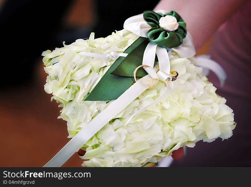 Gold wedding rings on white pillow