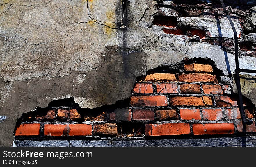 Crack in the plaster wall with the exposed brick