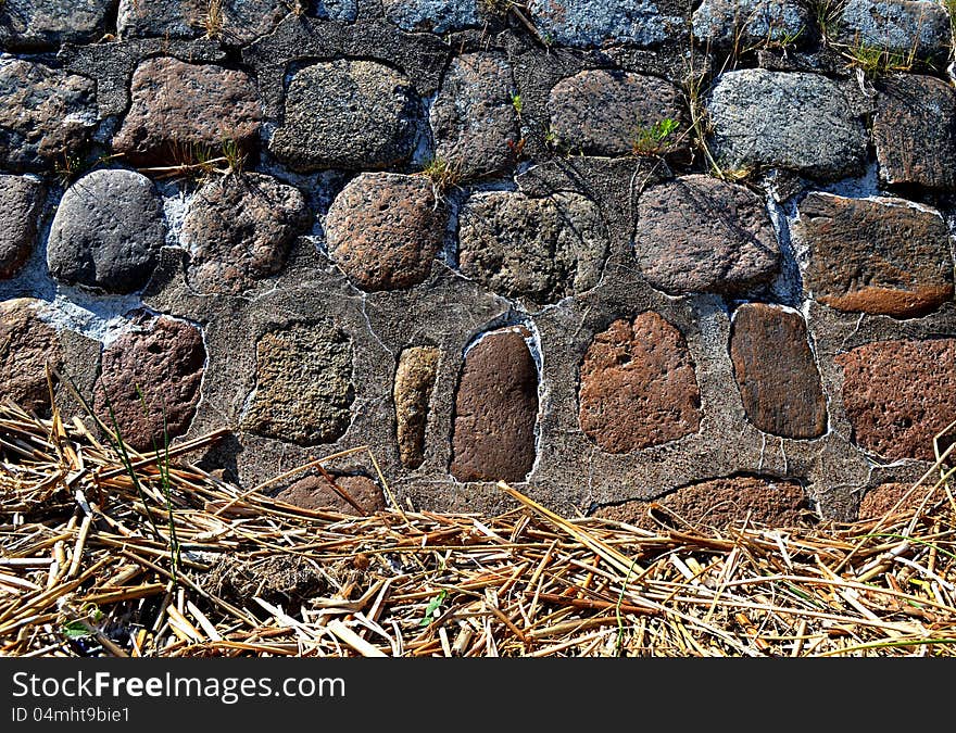 Background of the stone wall of large boulders and dry reed. Background of the stone wall of large boulders and dry reed