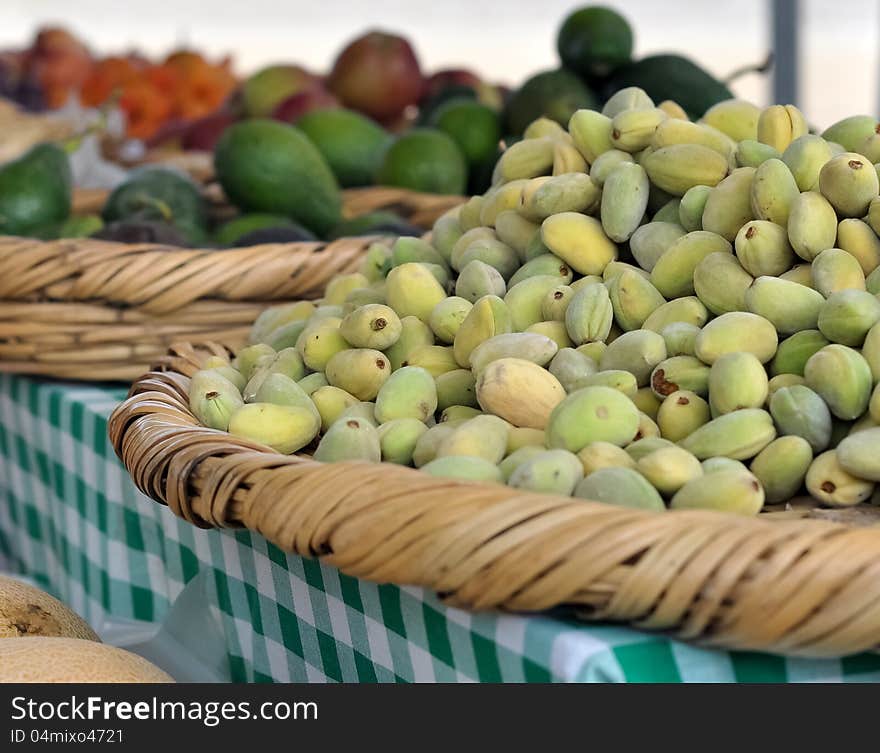 Green almonds displayed among other fruits and vegetables