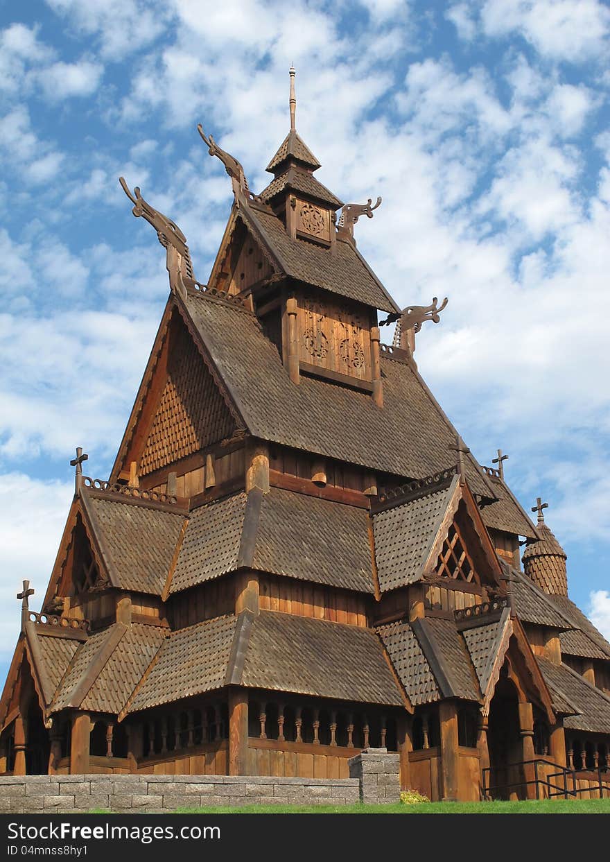 Close-up of a wooden Norwegian stave Christian church against a background of blue sky and clouds. Close-up of a wooden Norwegian stave Christian church against a background of blue sky and clouds.