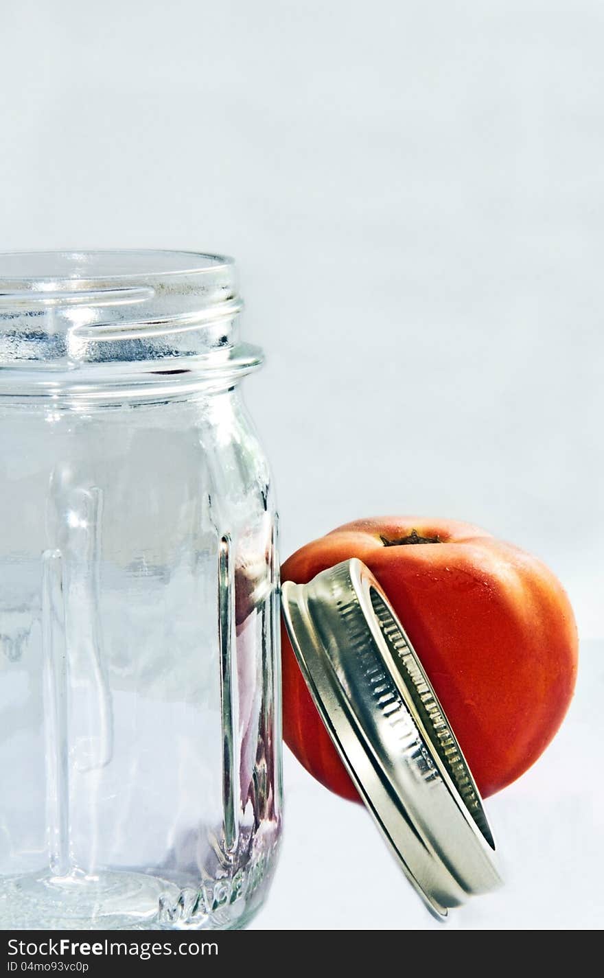 Pint jar with ring and tomato on white background. Pint jar with ring and tomato on white background