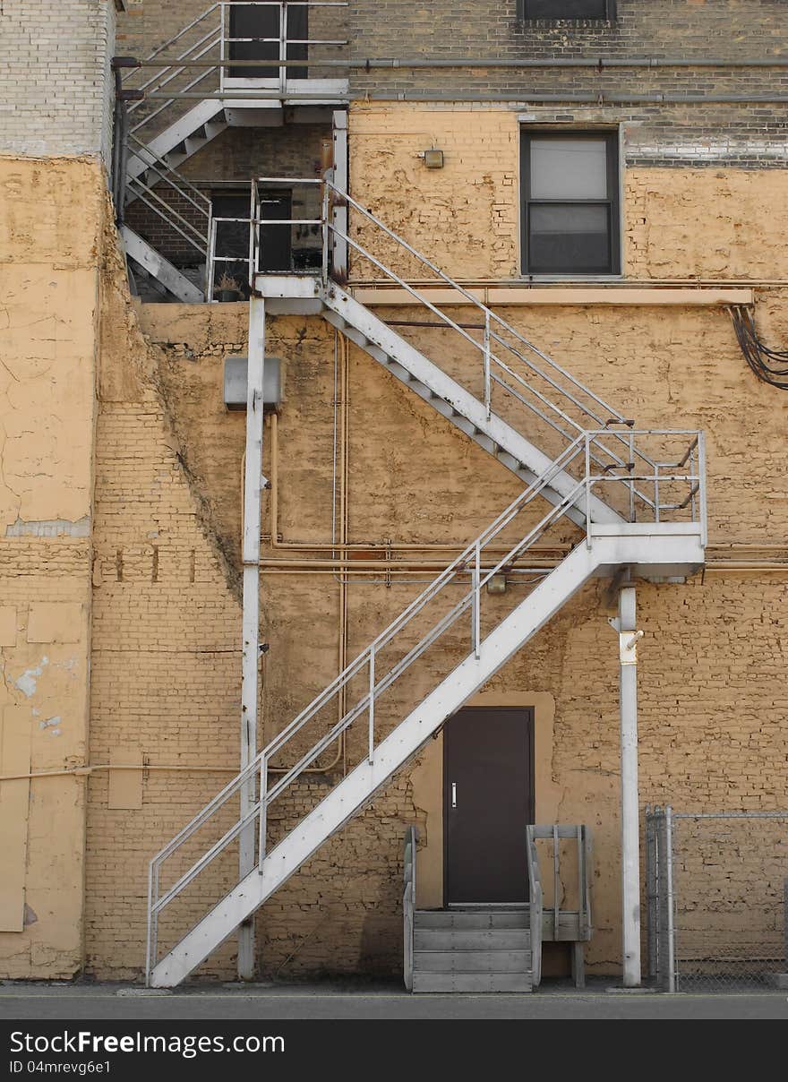 Outside metal fire escape steps on the side of an old brick building in an alley. Outside metal fire escape steps on the side of an old brick building in an alley.