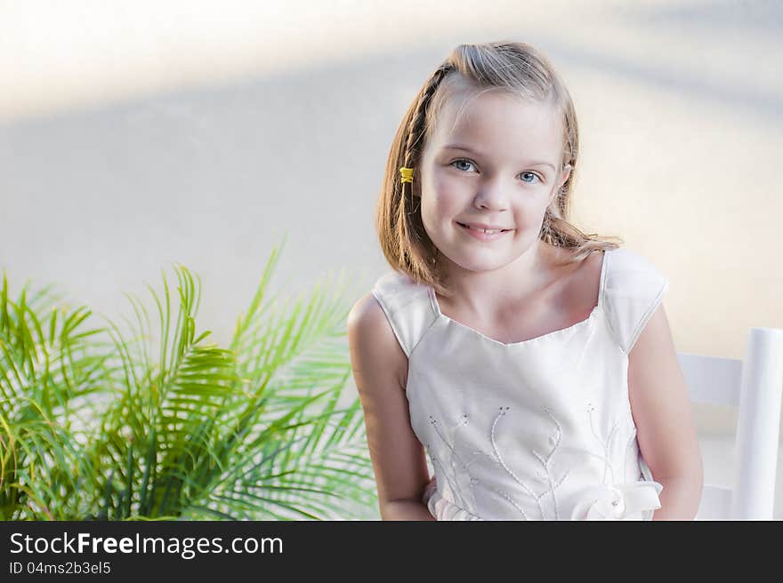 Young girl looking at the camera and posing for a picture by a plant. Young girl looking at the camera and posing for a picture by a plant.