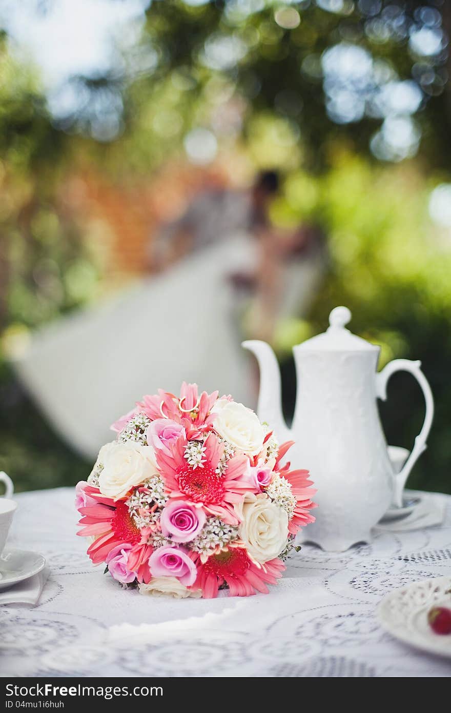 Bridal bouquet to the tea table in the background of newlyweds