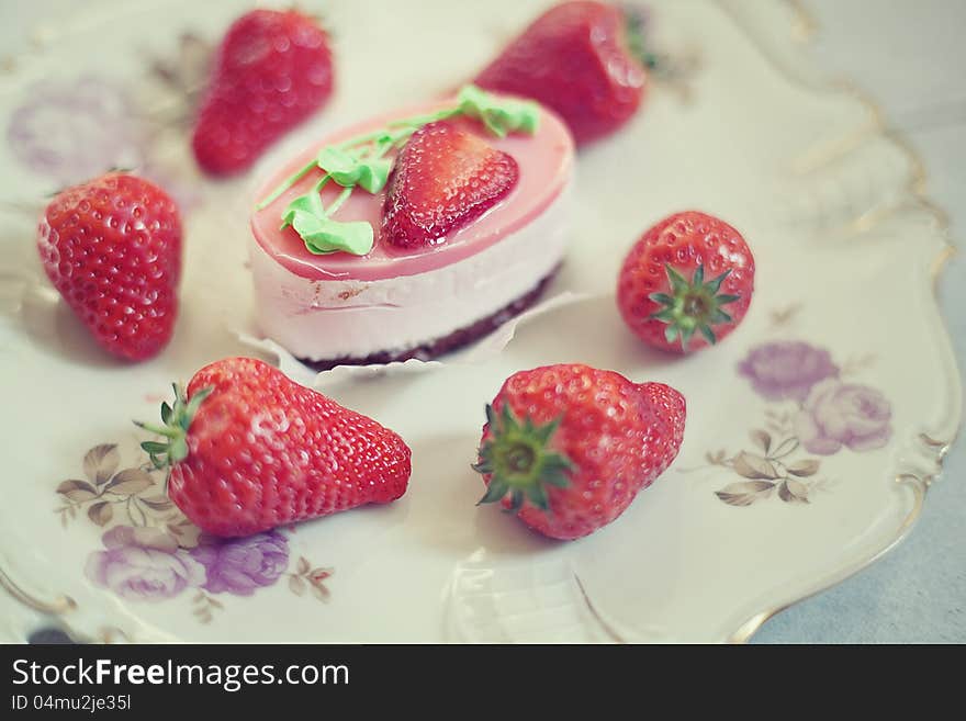 Strawberry cake on a plate surrounded by fresh strawberries