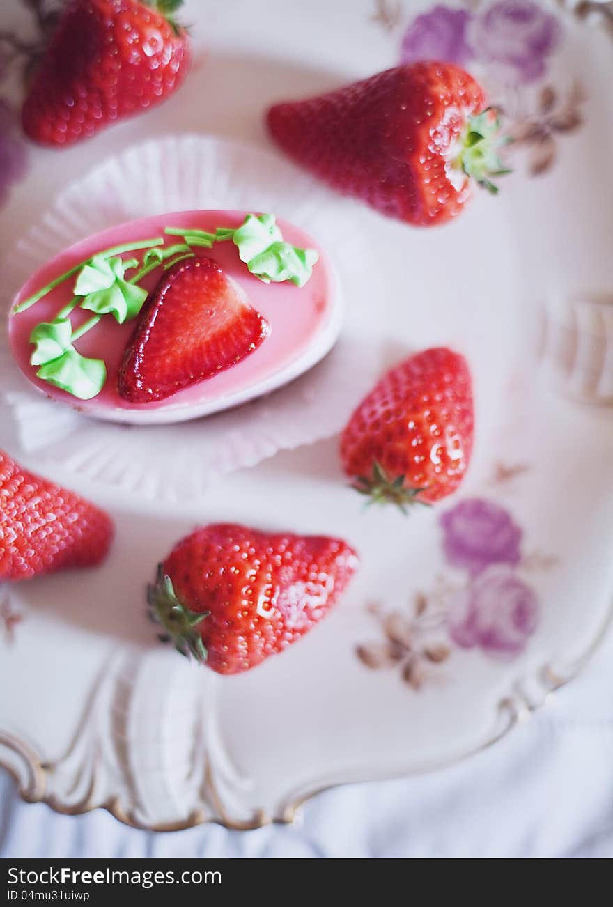 Strawberry cake on a plate surrounded by fresh strawberries