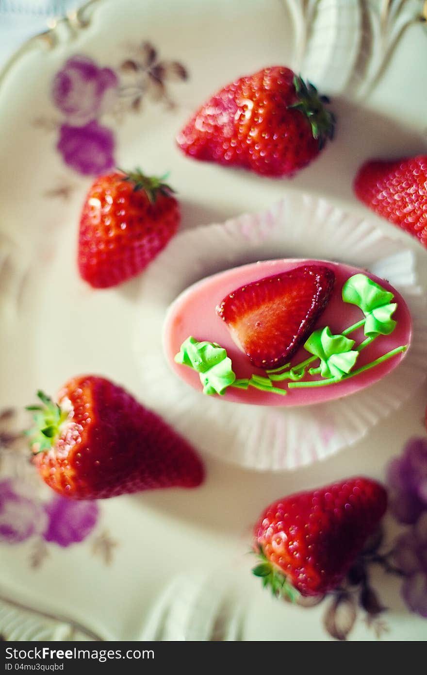 Strawberry cake on a plate surrounded by fresh strawberries