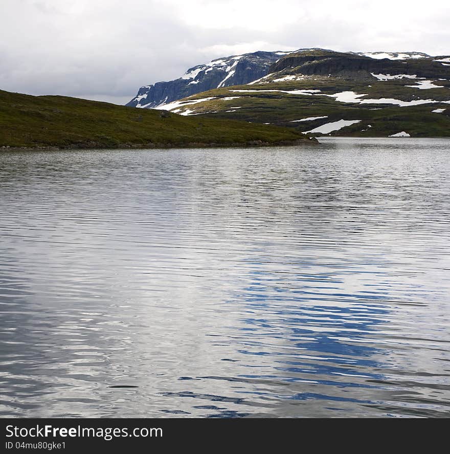 Norwegian landscape with a mountain on background and mountain lake