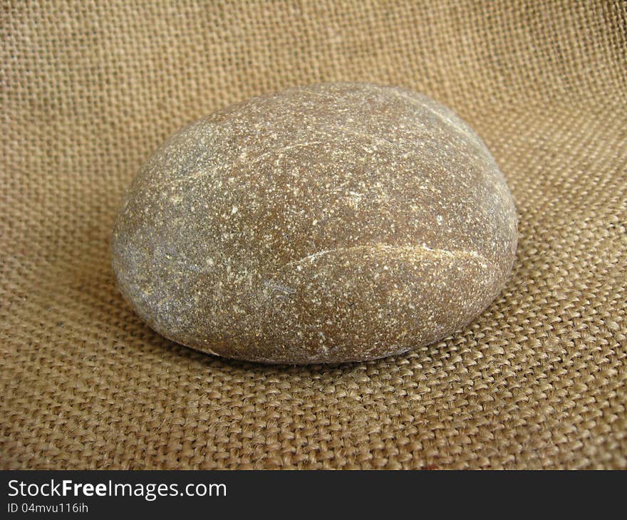 Grey stone laying on a brown background. Grey stone laying on a brown background