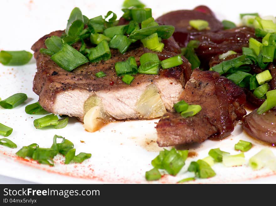 Grilled pork steak with green onion on white plate. Grilled pork steak with green onion on white plate.