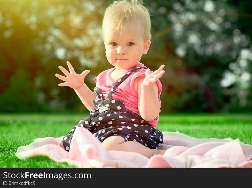 Cute playful blond 1.2 years old girl sitting on green grass outdor. Cute playful blond 1.2 years old girl sitting on green grass outdor