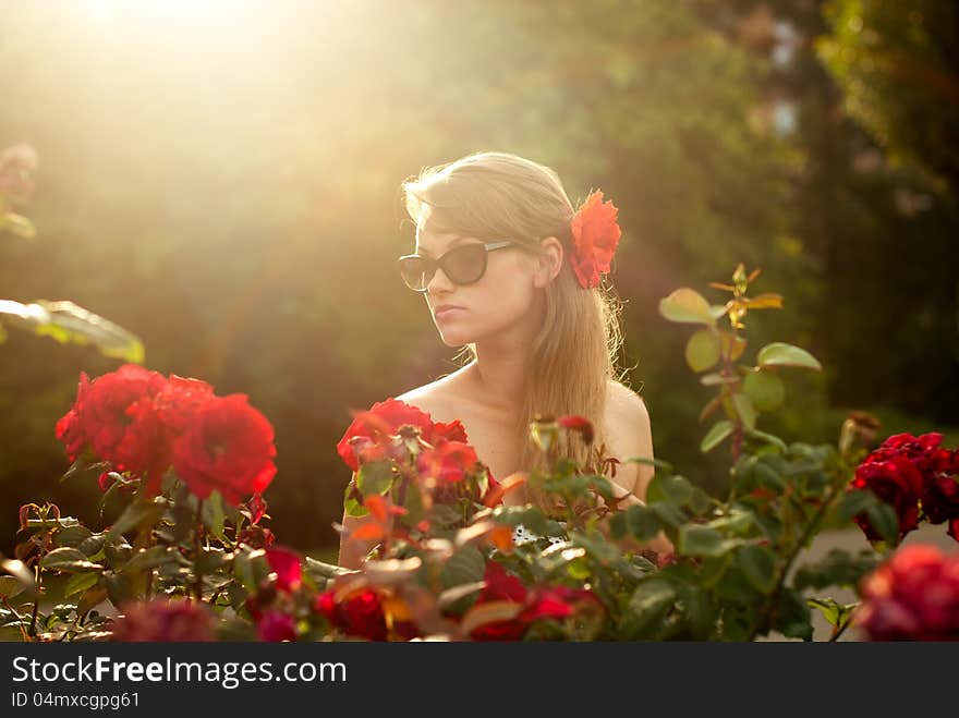 Young model in flower garden smelling red roses. Young model in flower garden smelling red roses