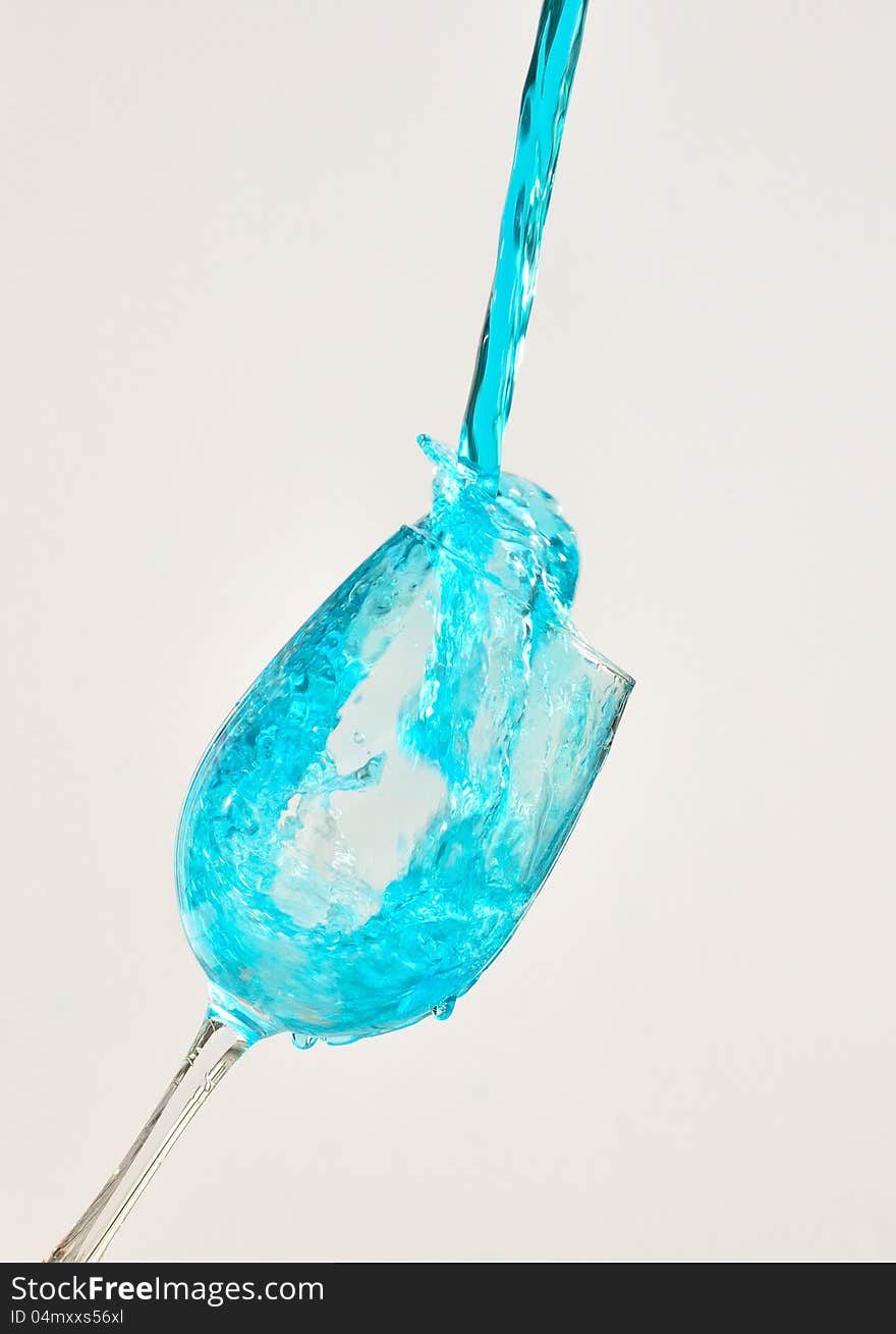 Blue water splashing out of a wine glass. Blue water splashing out of a wine glass