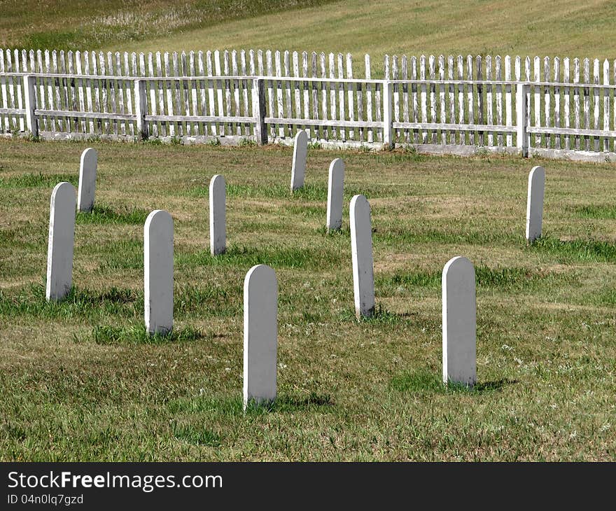 Old cemetery in a prairie field, with white headstones and an old wooden white fence in the background. This was a burial place of cavalry soldiers in the 1800’s. Old cemetery in a prairie field, with white headstones and an old wooden white fence in the background. This was a burial place of cavalry soldiers in the 1800’s.