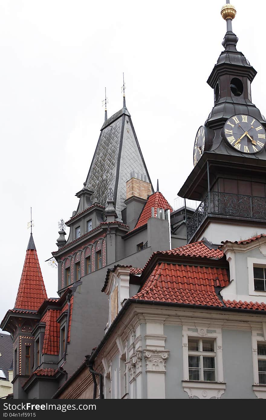 Classical Prague architecture. Gray gothic house with red tiling roof and clock tower, Czech Republic