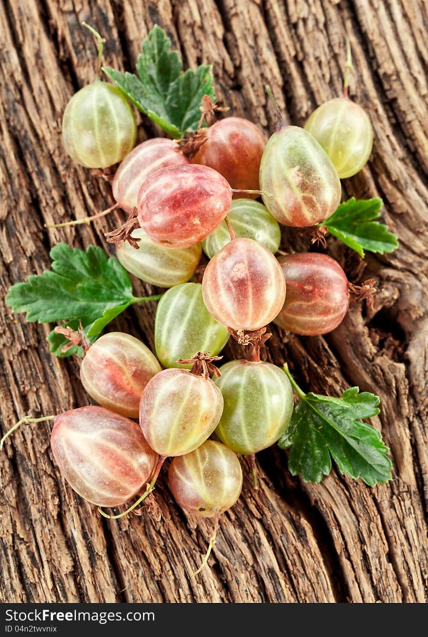 Gooseberries with leaves on a old wooden table.