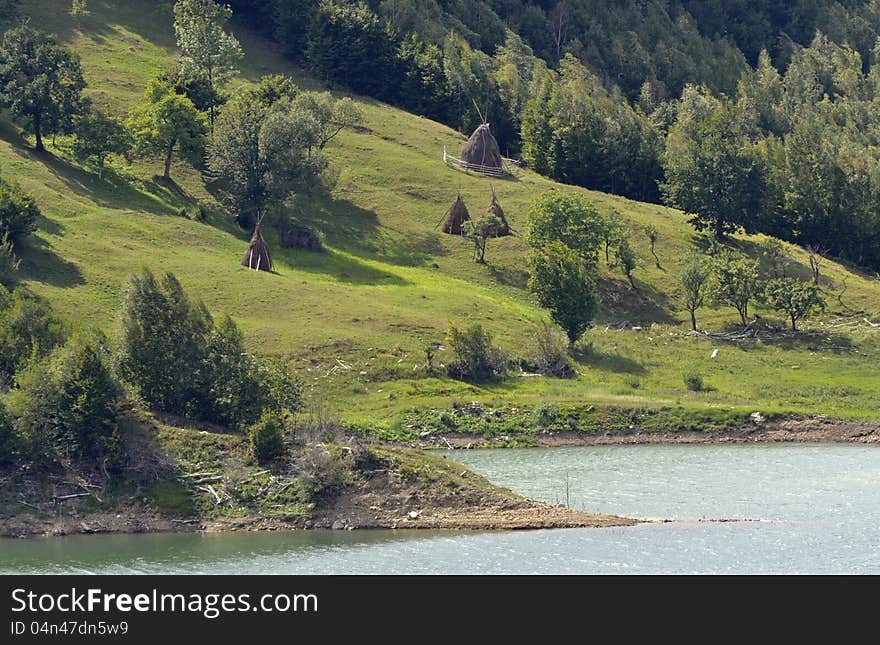 Haycock on green hill near Siriu lake and forest rural agriculture. Siriu valley and lake is a touristic attraction in middle Romania, Carpathian mountains. Haycock on green hill near Siriu lake and forest rural agriculture. Siriu valley and lake is a touristic attraction in middle Romania, Carpathian mountains.